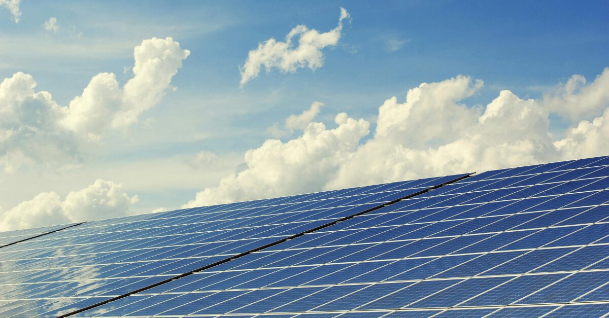 Solar panels in front of a blue sky with clouds which represents Australia's renewable energy transition.